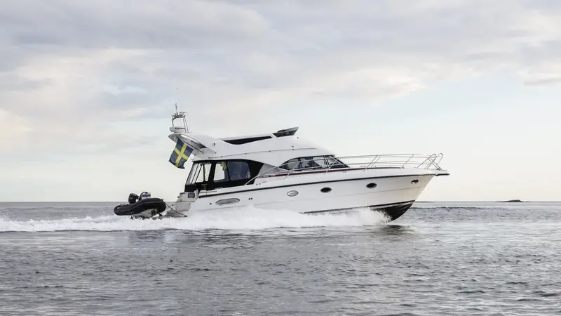 Motorbåt i fart med en svart ribbåt på badbryggan, skärgården i bakgrunden